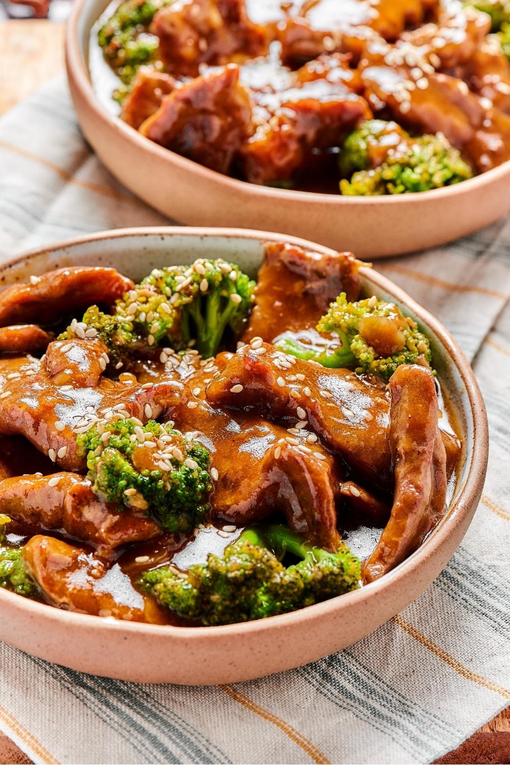 A bowl of beef and broccoli stir fry with another bowl of beef and broccoli stir fry behind it.