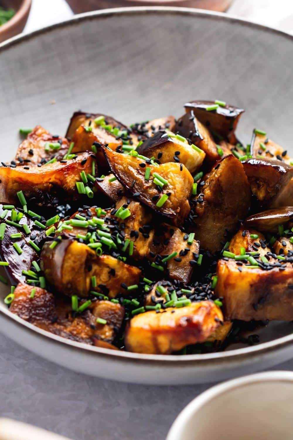 Sauteed eggplant slices in a white bowl.