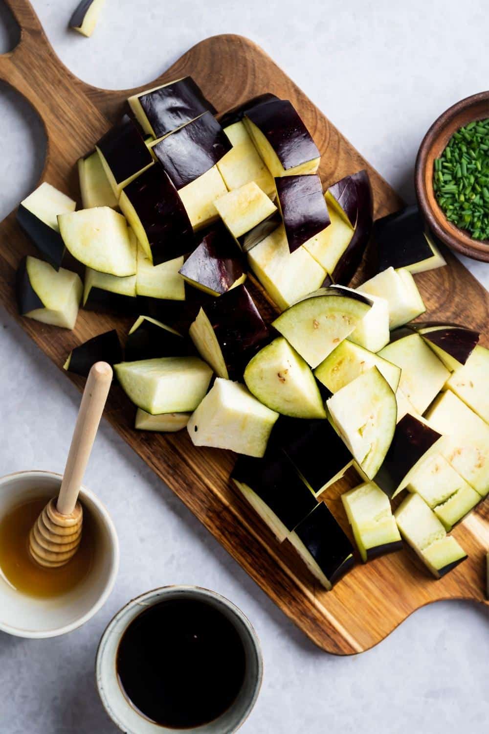 A bunch of diced eggplant squares on a wooden cutting board.