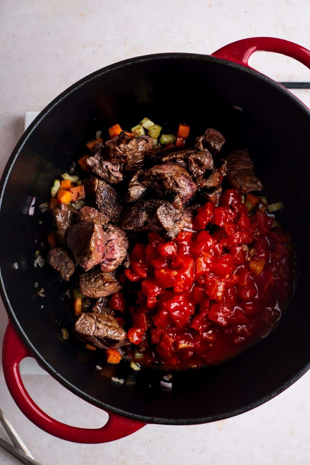 Crushed tomatoes, Carne picada, chopped celery, carrots, and onion and a Dutch oven.