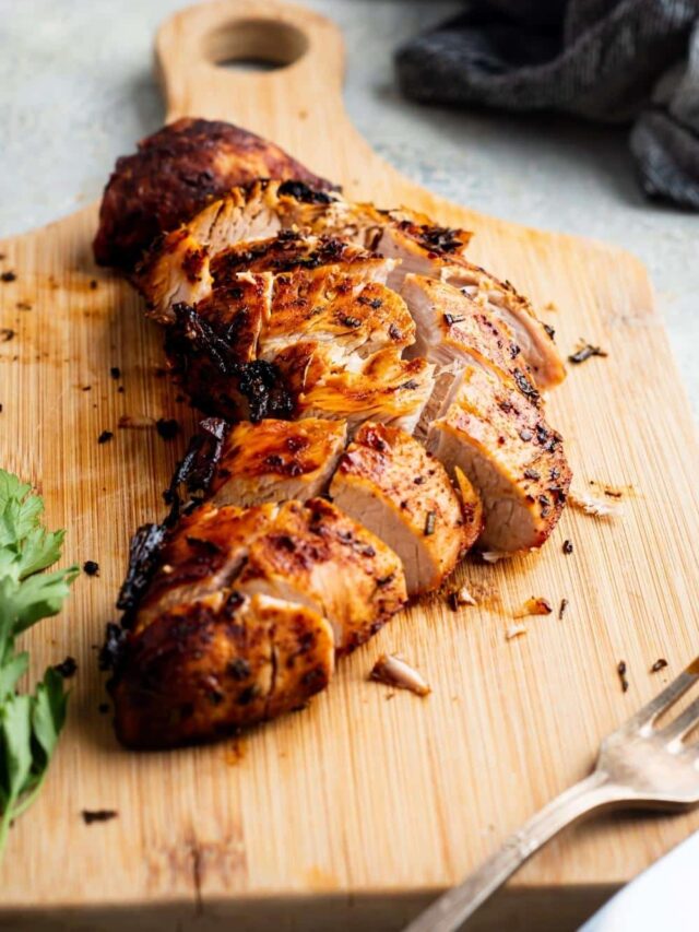 Turkey tenderloin sliced on a wooden cutting board.