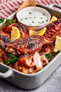 Part of a casserole dish with baked turkey wings in it.