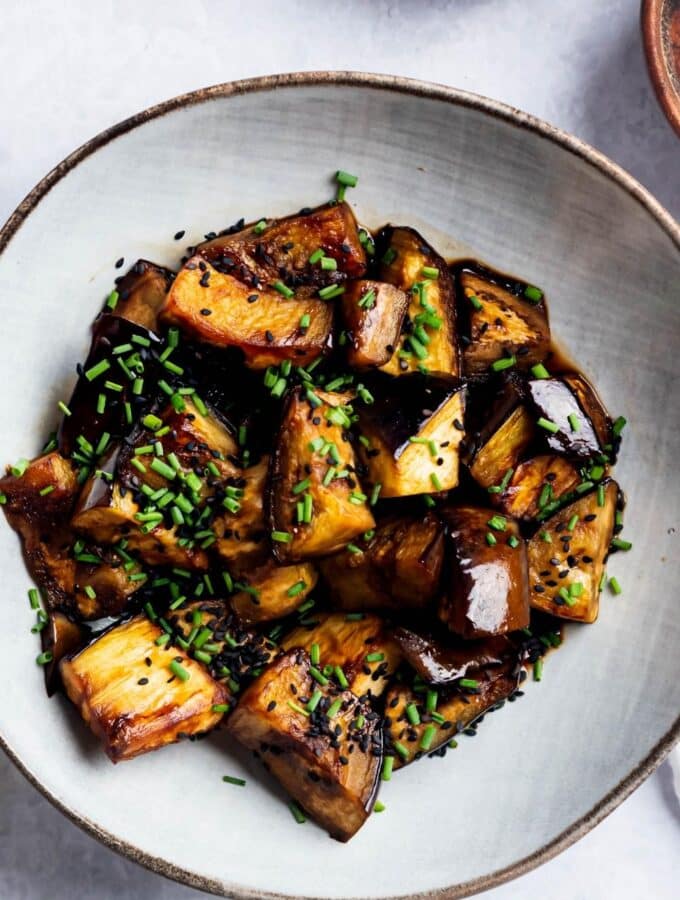 Eggplant slices in a white bowl on a white counter.