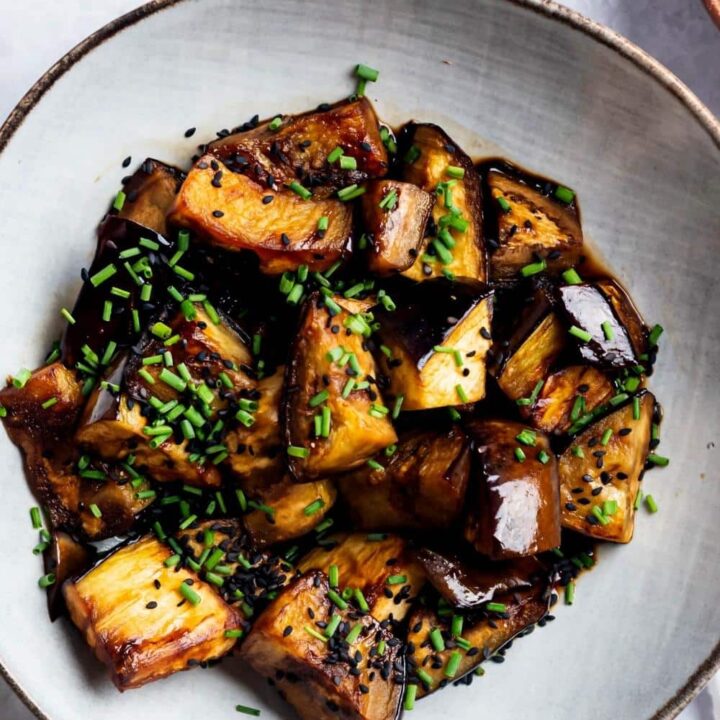 Eggplant slices in a white bowl on a white counter.