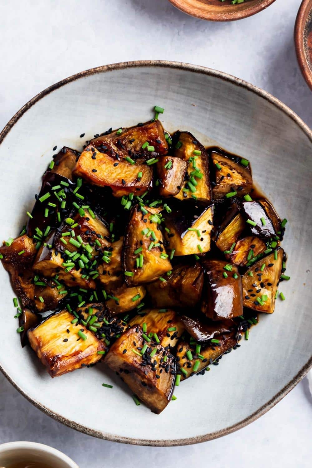 Eggplant slices in a white bowl on a white counter.