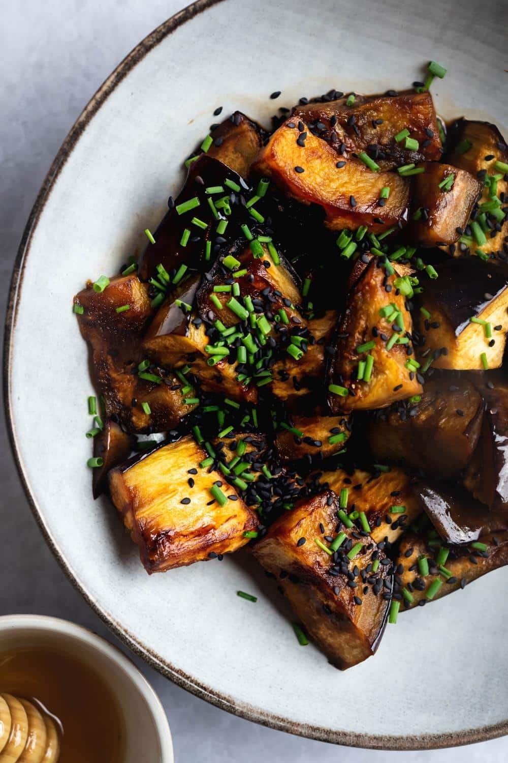 Part of a white plate with sauteed eggplant squares on it.