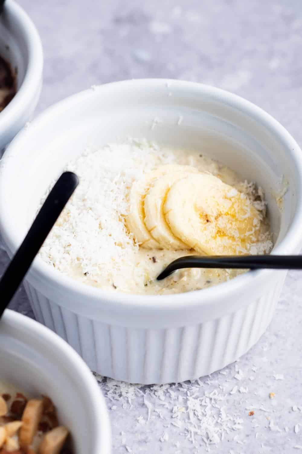 Shredded coconut in a white bowl that is filled with protein overnight oats