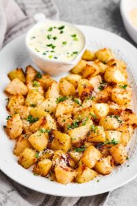 Roasted kohlrabi and a yogurt dressing on top of an oval plate.