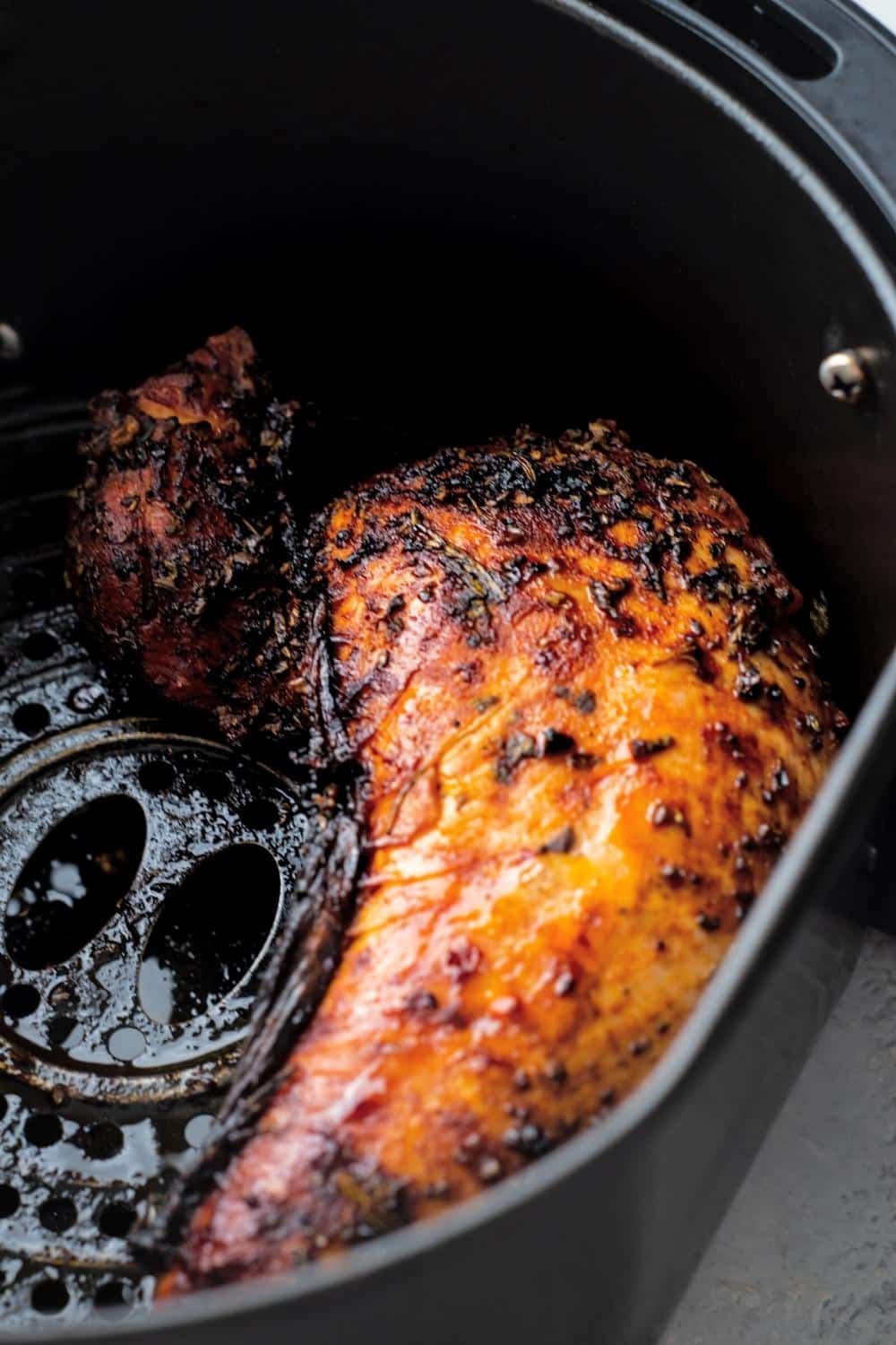 Cooked turkey tenderloin in an air fryer basket.