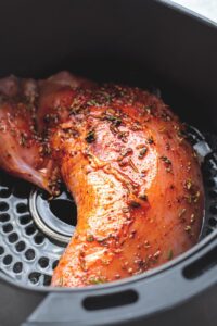 Turkey tenderloin in an air fryer basket.