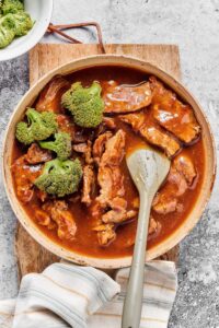 A bowl with beef and broccoli in it with stir fry sauce.