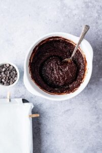 A bowl of almond flour brownie batter with a spoon in it.