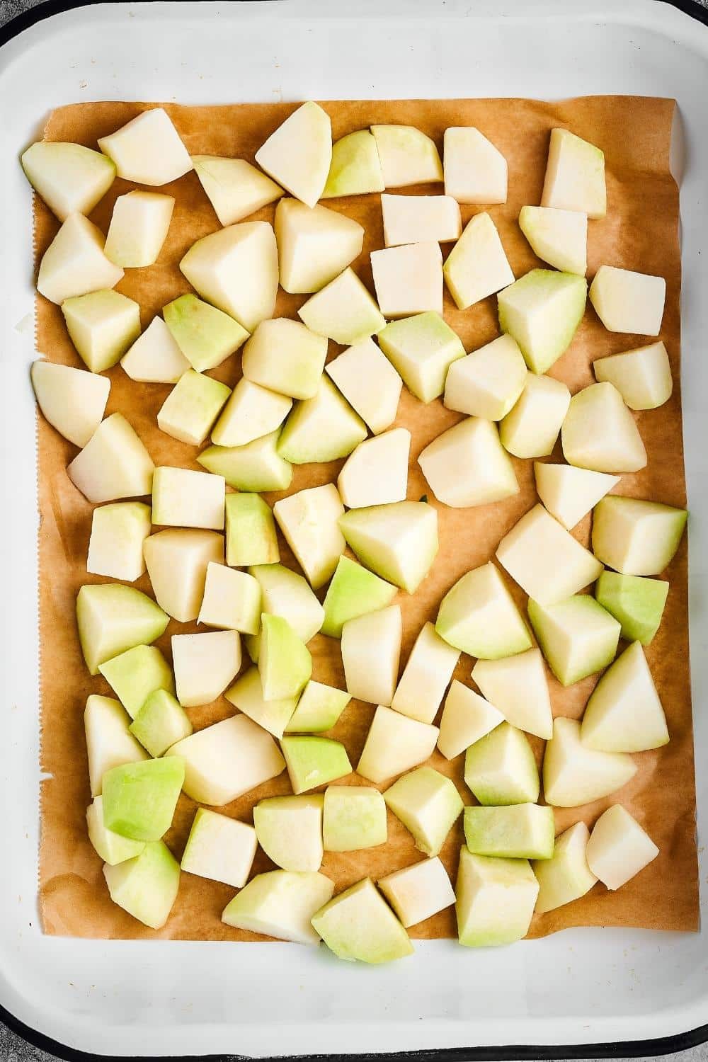 Kohlrabi squares on a sheet of parchment paper on top of a baking dish.