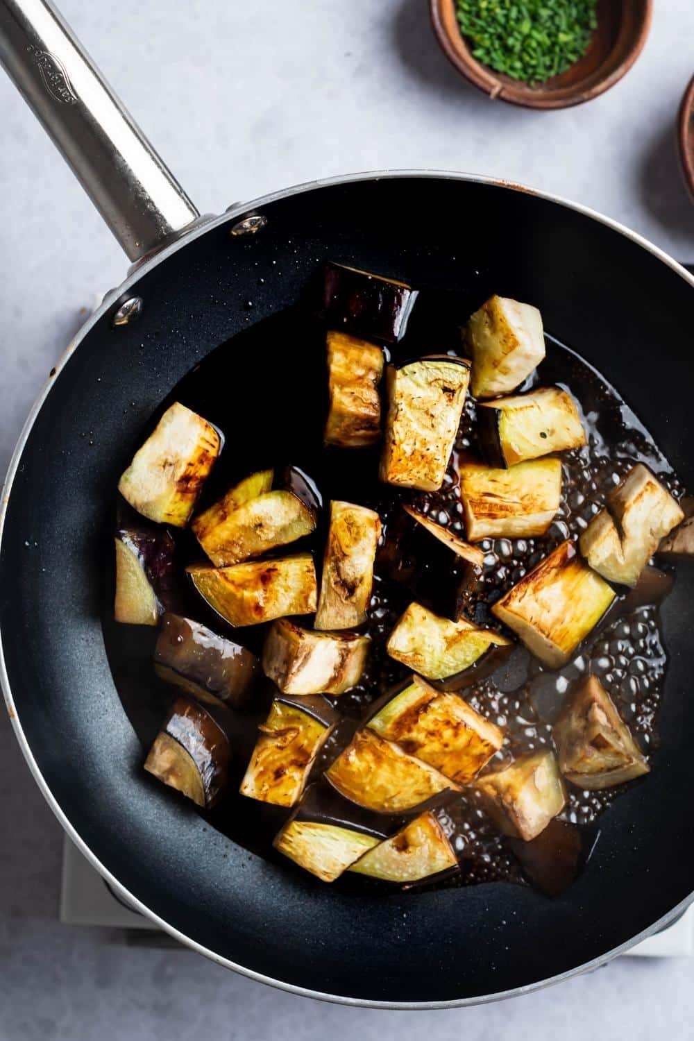 Eggplant slices roasting in a skillet with oil.