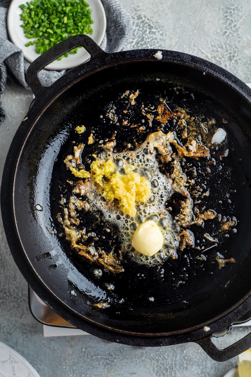 A skillet with butter, garlic, and lemon cooking in it.