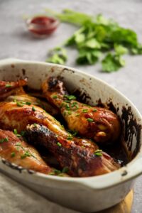 Baked chicken legs in part of a casserole dish.