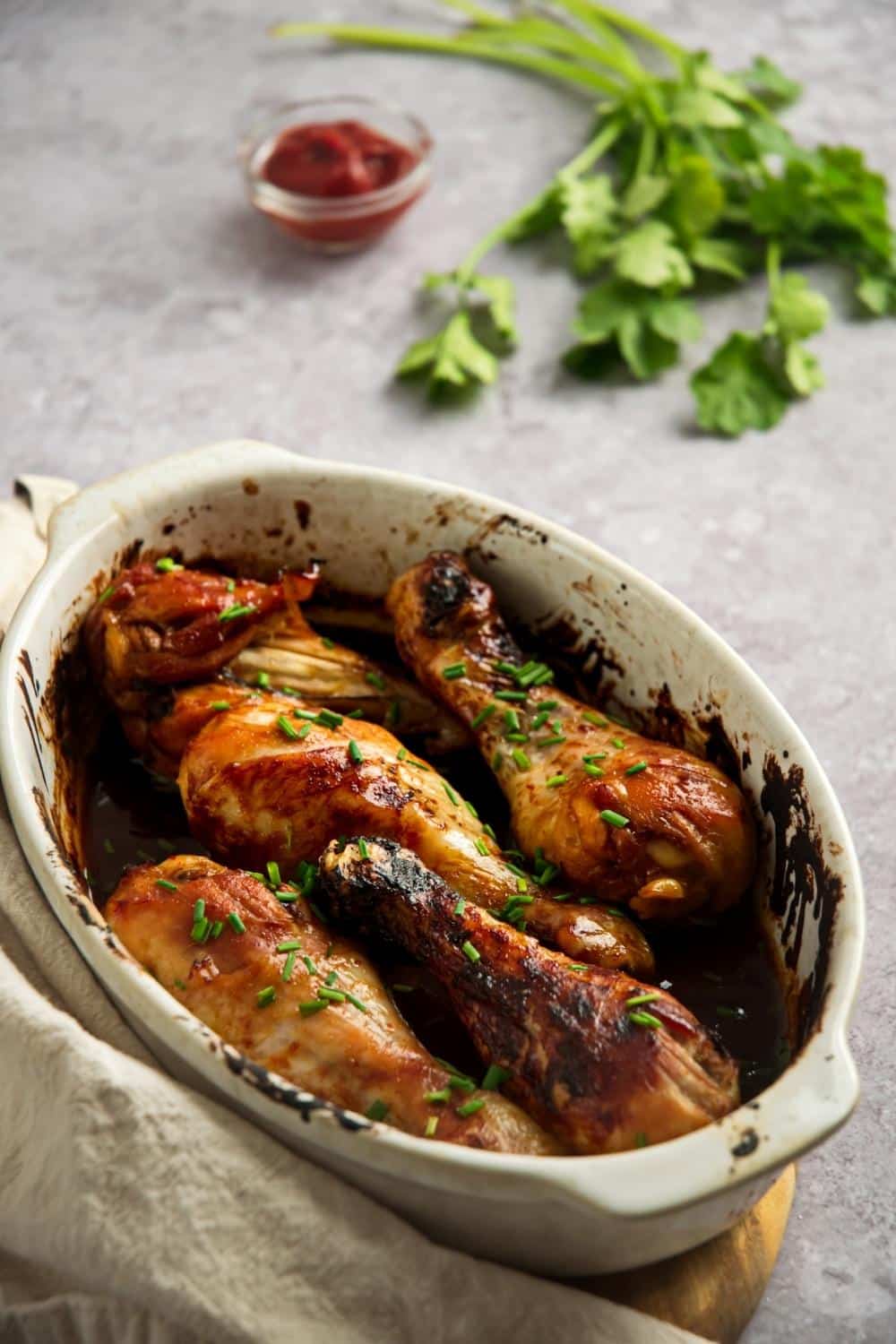 Baked chicken legs in a white casserole dish.