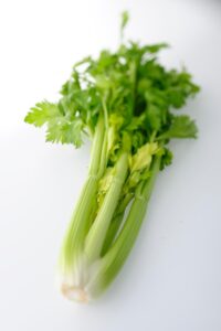 A bundle of celery on a white table.