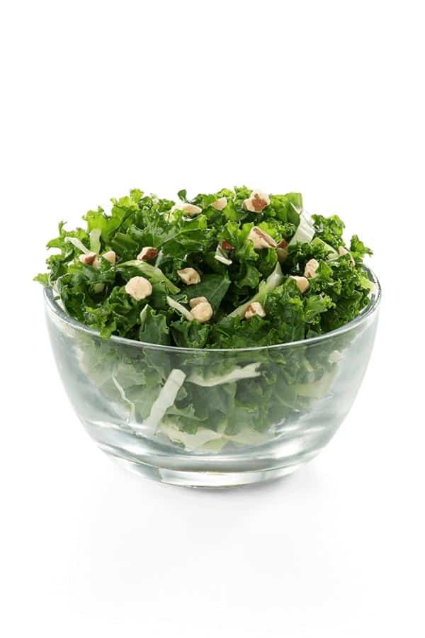 A glass bowl filled with a kale salad.