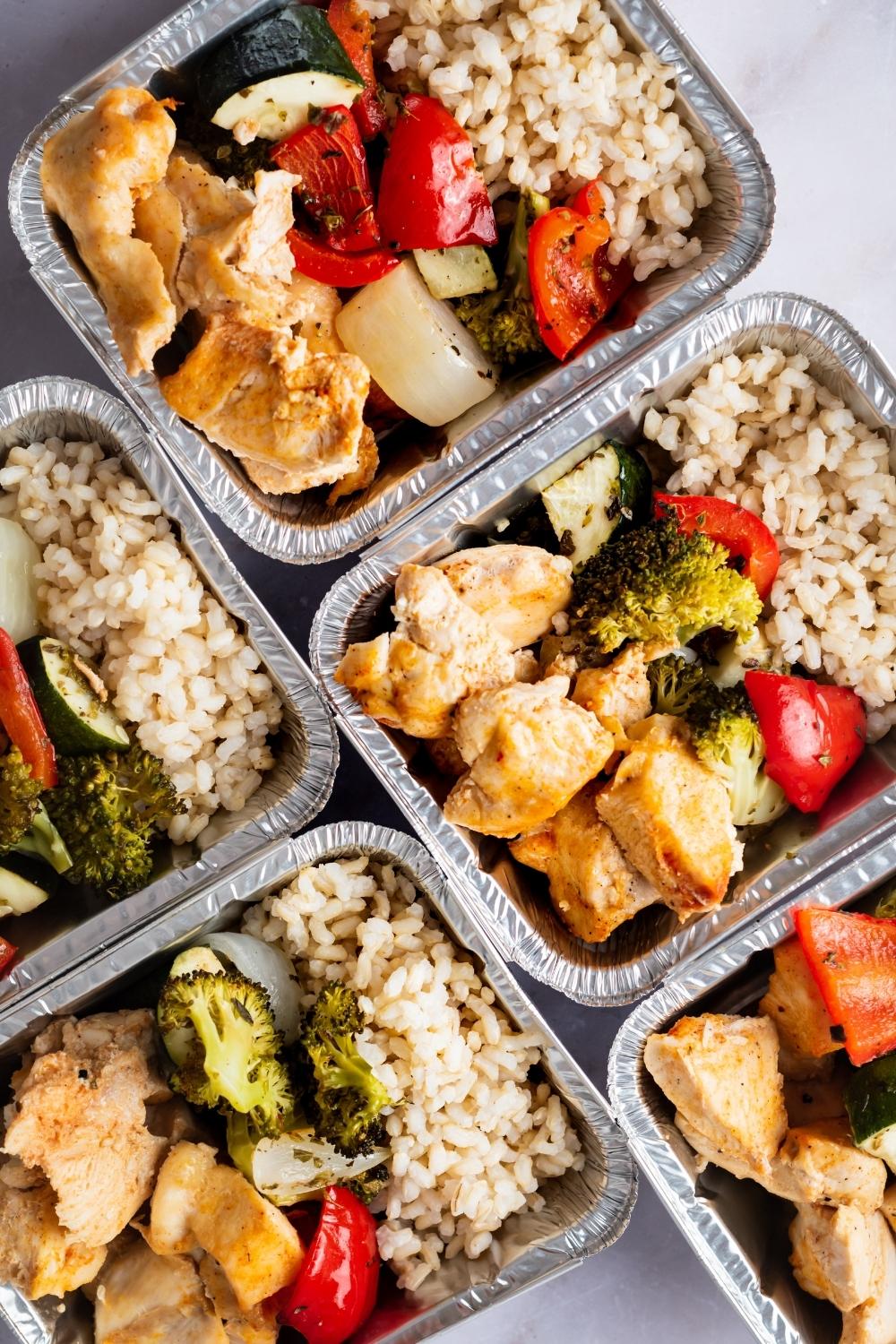 Four containers of chicken, rice, and veggies.