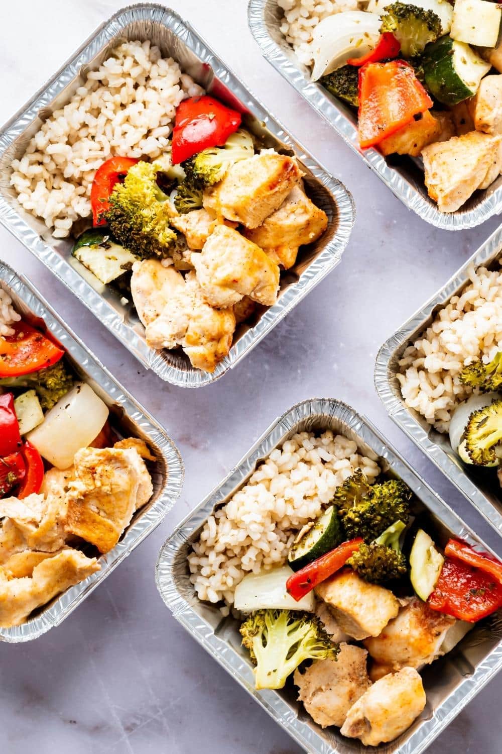 A few containers filled with chicken, rice, and veggies.