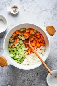 Diced carrots, celery, and onions in a bowl with broth in it.