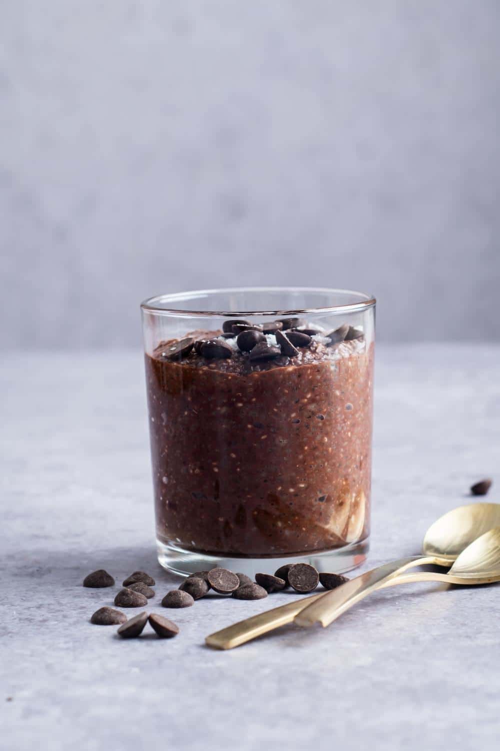 A cup that has chocolate protein pudding in it with chocolate chips on top.