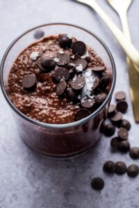 Chocolate chips and sea salt on chocolate protein pudding in a glass.