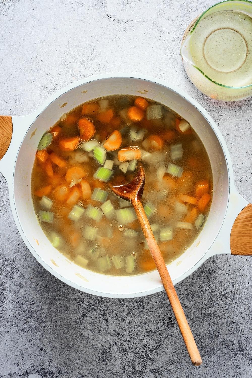 Broth with diced celery, carrots, and onions in it.