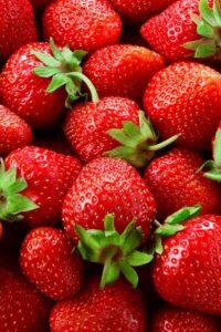 A bunch of strawberries in a pile touching one another.