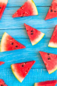 Five watermelon slices on a blue wooden table.