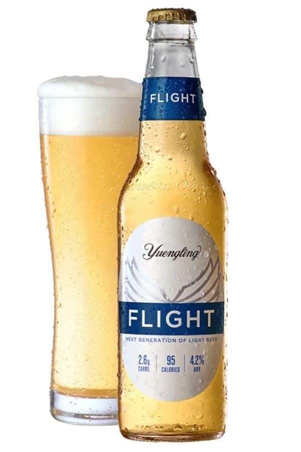 A bottle of Yuengling flight with a glass filled with a beer to the left of it.