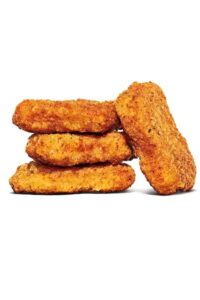 Three chicken nuggets stacked on top of each other with one chicken nugget against the three.