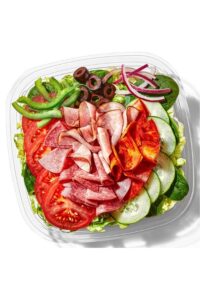 Salami, Ham, and pepperoni with tomato, olives, and onion on top of lettuce in a container.