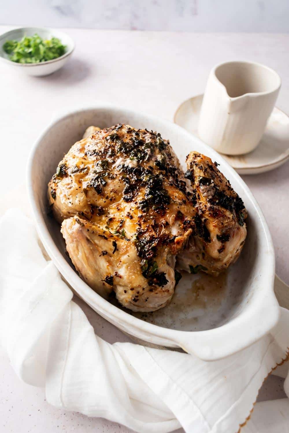 A white casserole dish with a cornish hen in it.