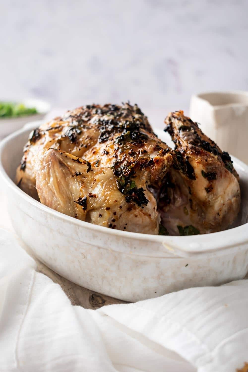 A cornish hen that is in a white casserole dish.