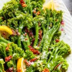 A bunch of broccolini on part of a white plate.