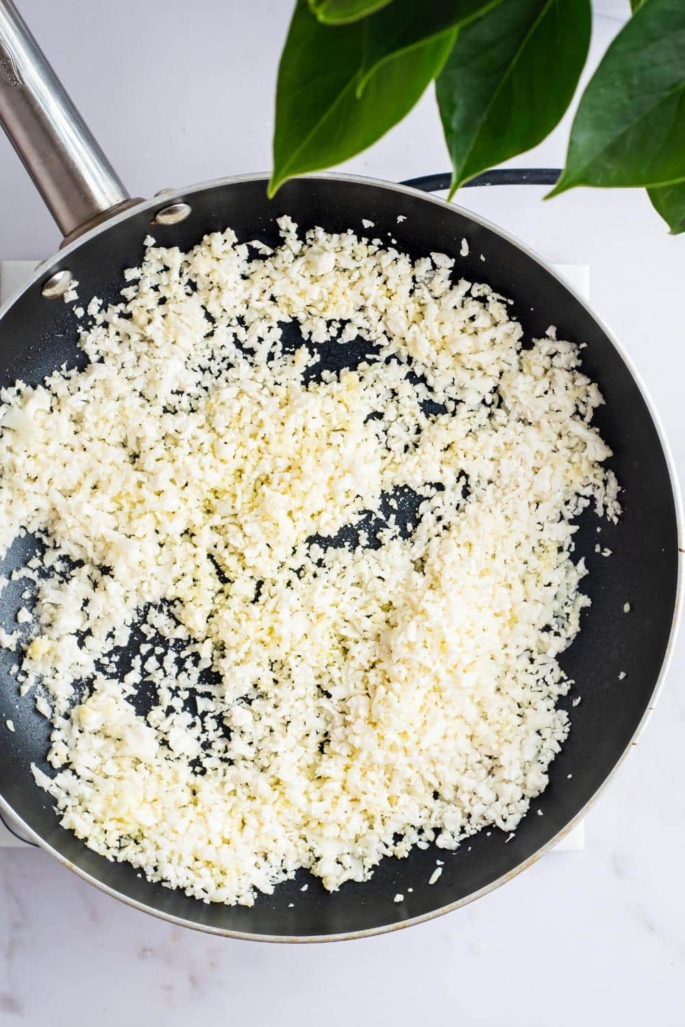 Cauliflower rice cooking in a skillet.
