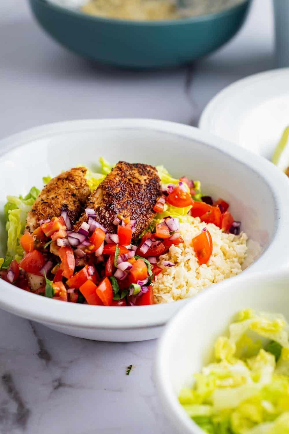 Chicken, pico, cauliflower rice, and lettuce in a bowl.