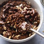 A spoon scooping protein oatmeal from a bowl filled with the chocolate oatmeal.