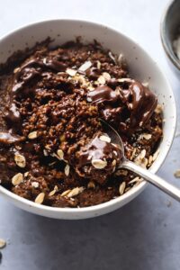 A spoon scooping protein oatmeal from a bowl filled with the chocolate oatmeal.
