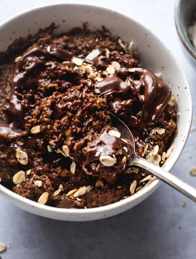 A spoon scooping protein oatmeal from a bowl filled with the chocolate oatmeal.