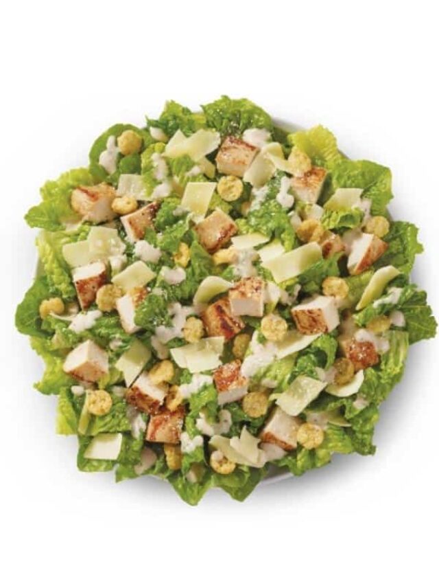 A caesar salad with croutons and parmesan cheese slices.