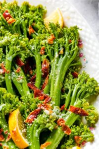 A few stalks of broccolini on part of a white plate.