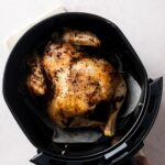 A cooked cornish hen in an air fryer basket.