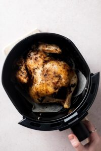 A cooked cornish hen in an air fryer basket.