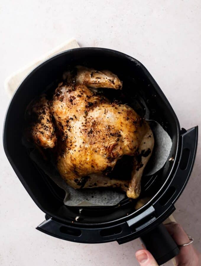 A cooked cornish hen in an air fryer basket.