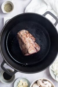 Bottom round roast cooking in a Dutch oven.