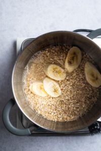 Sliced bananas, water, and oats in a pot.