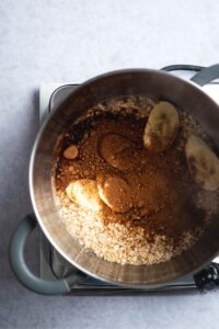 Sliced bananas, protein powder, and oats in a pot.